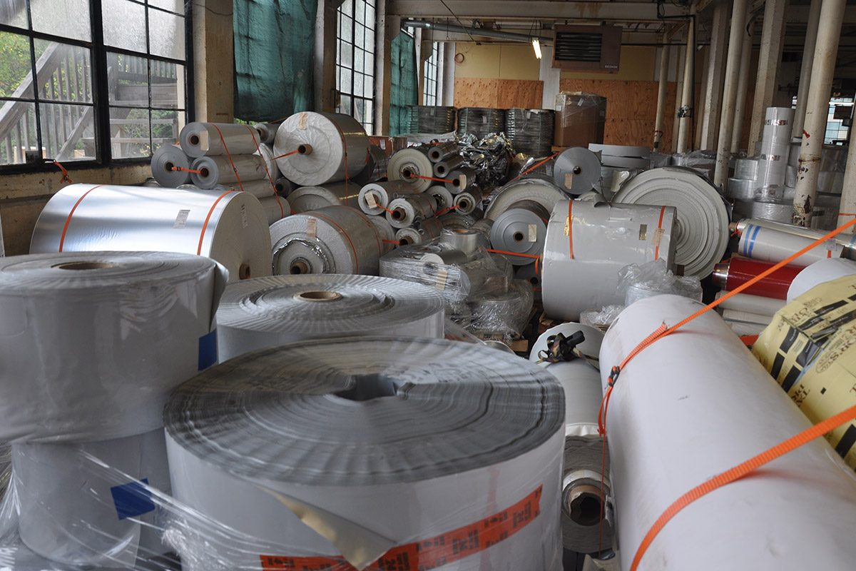 Rolls of surplus film and foil roll stock strapped and stacked in a warehouse
